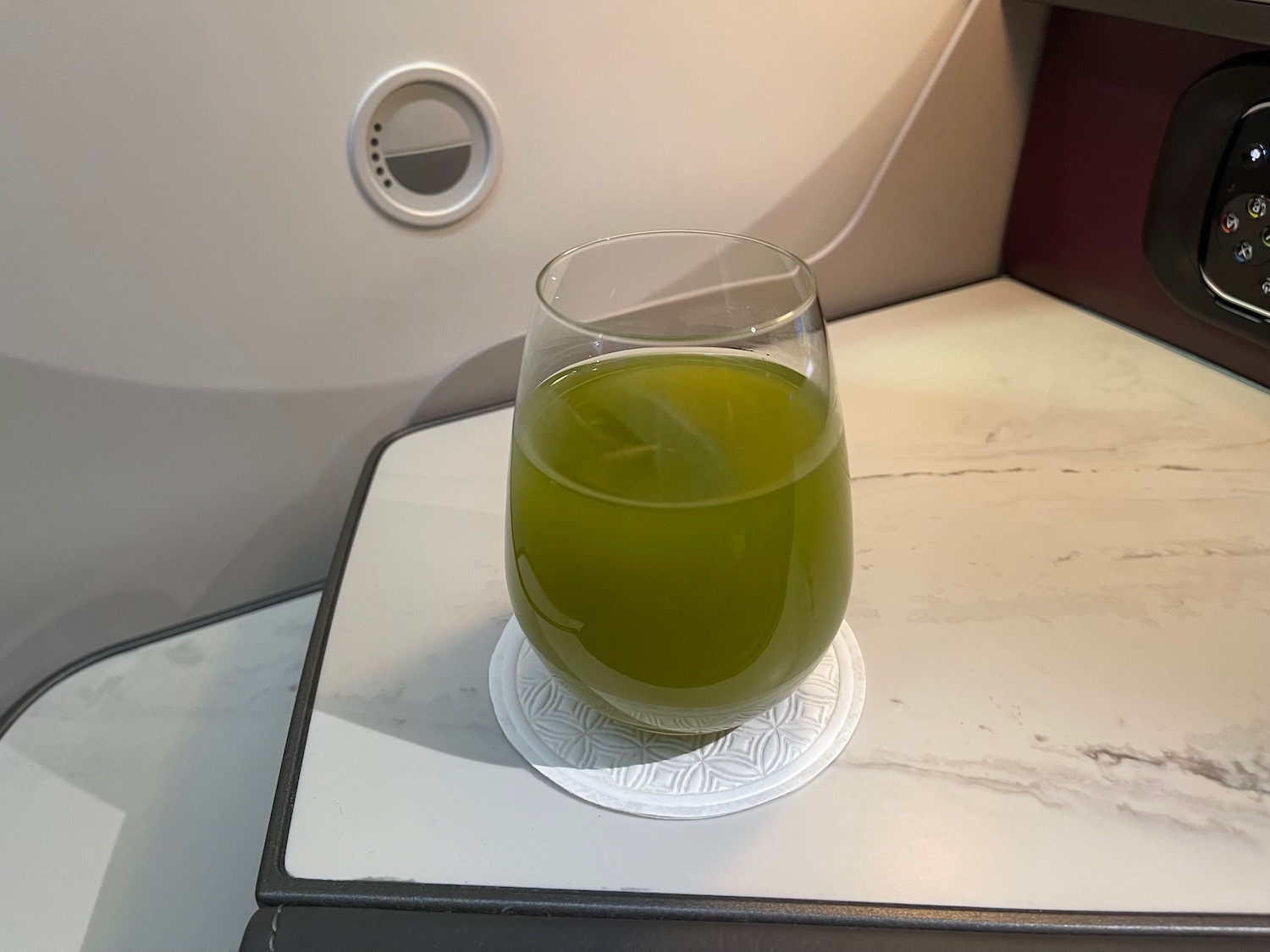 a glass of green liquid on a coaster