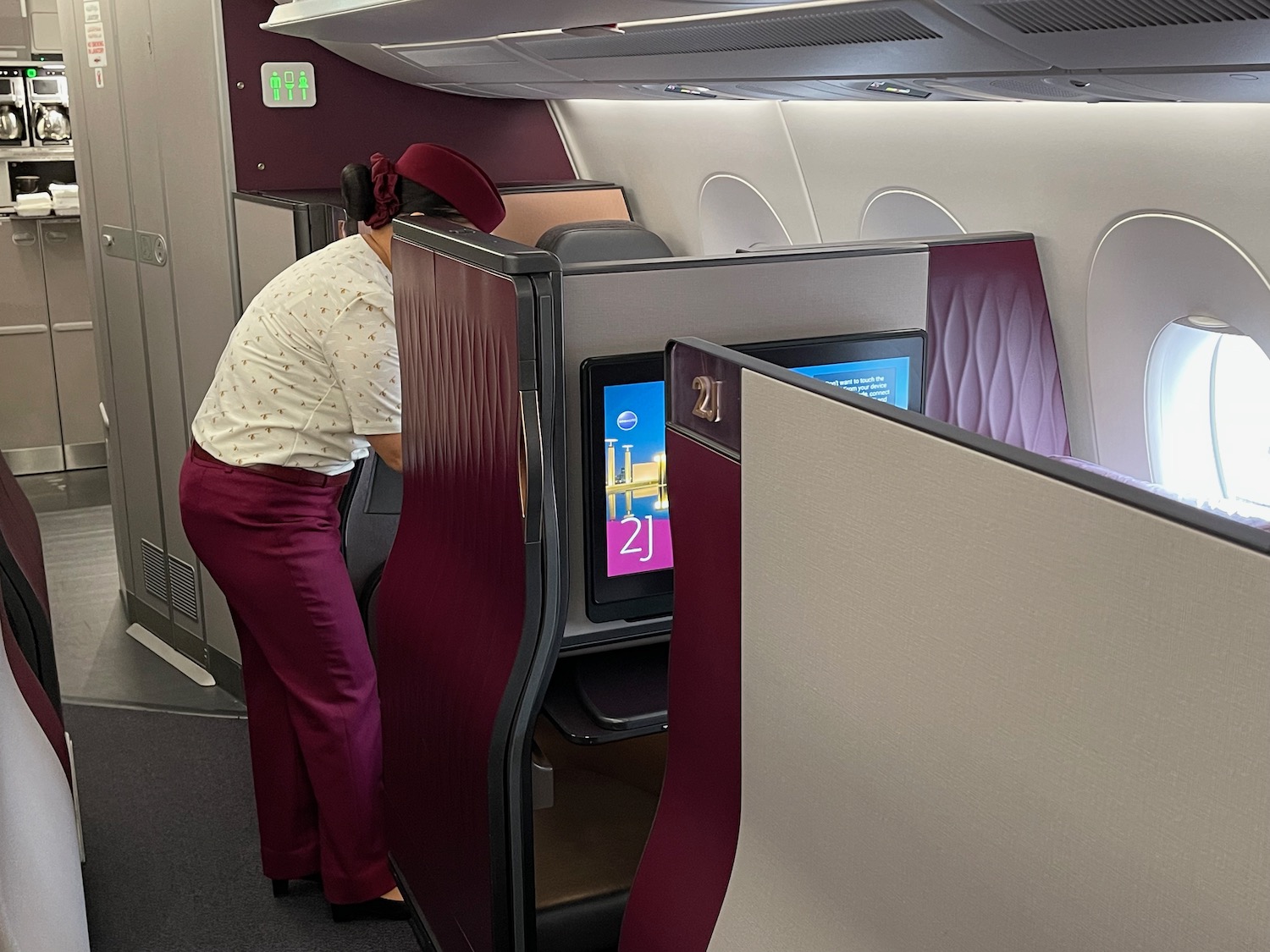 a woman in a white shirt and maroon pants standing in an airplane