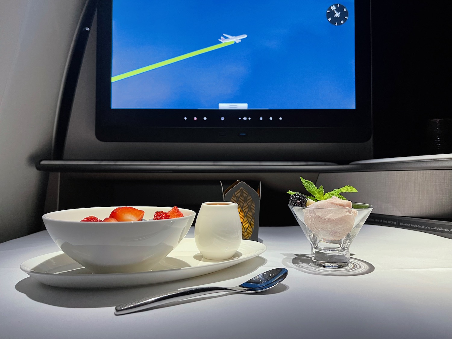 a bowl of fruit and ice cream on a table with a television