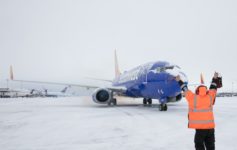 a man in an orange vest pointing at an airplane