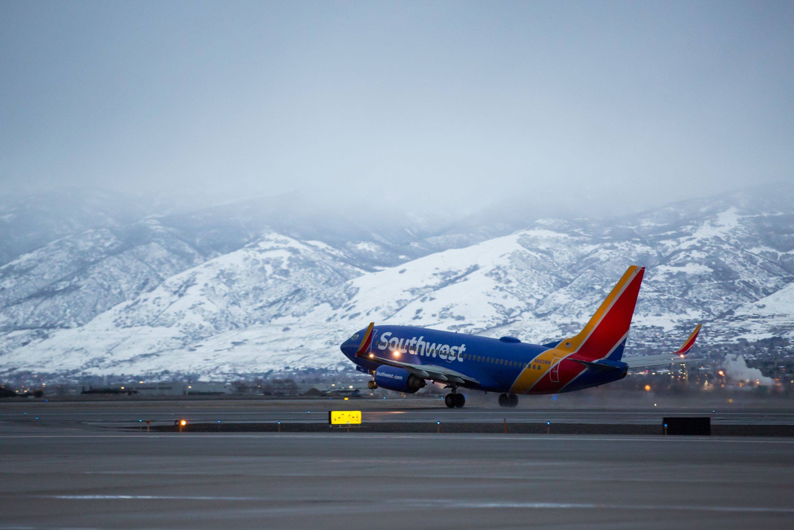 a plane taking off from a runway with mountains in the background