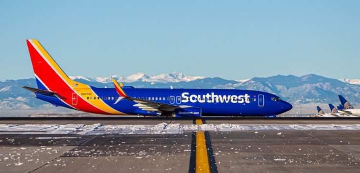 a blue and red airplane on a runway with snow on the ground