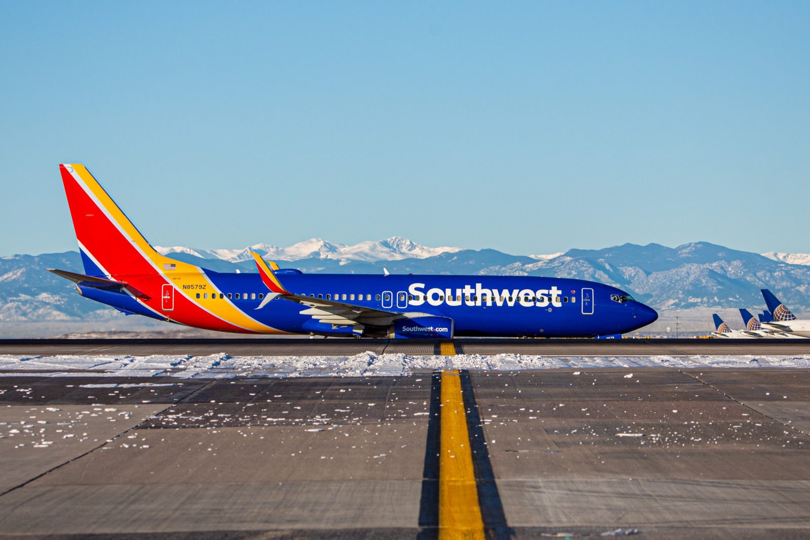 a blue and red airplane on a runway with snow on the ground