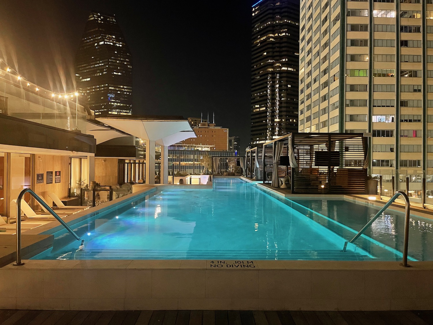 a pool with a blue light in the middle of a city