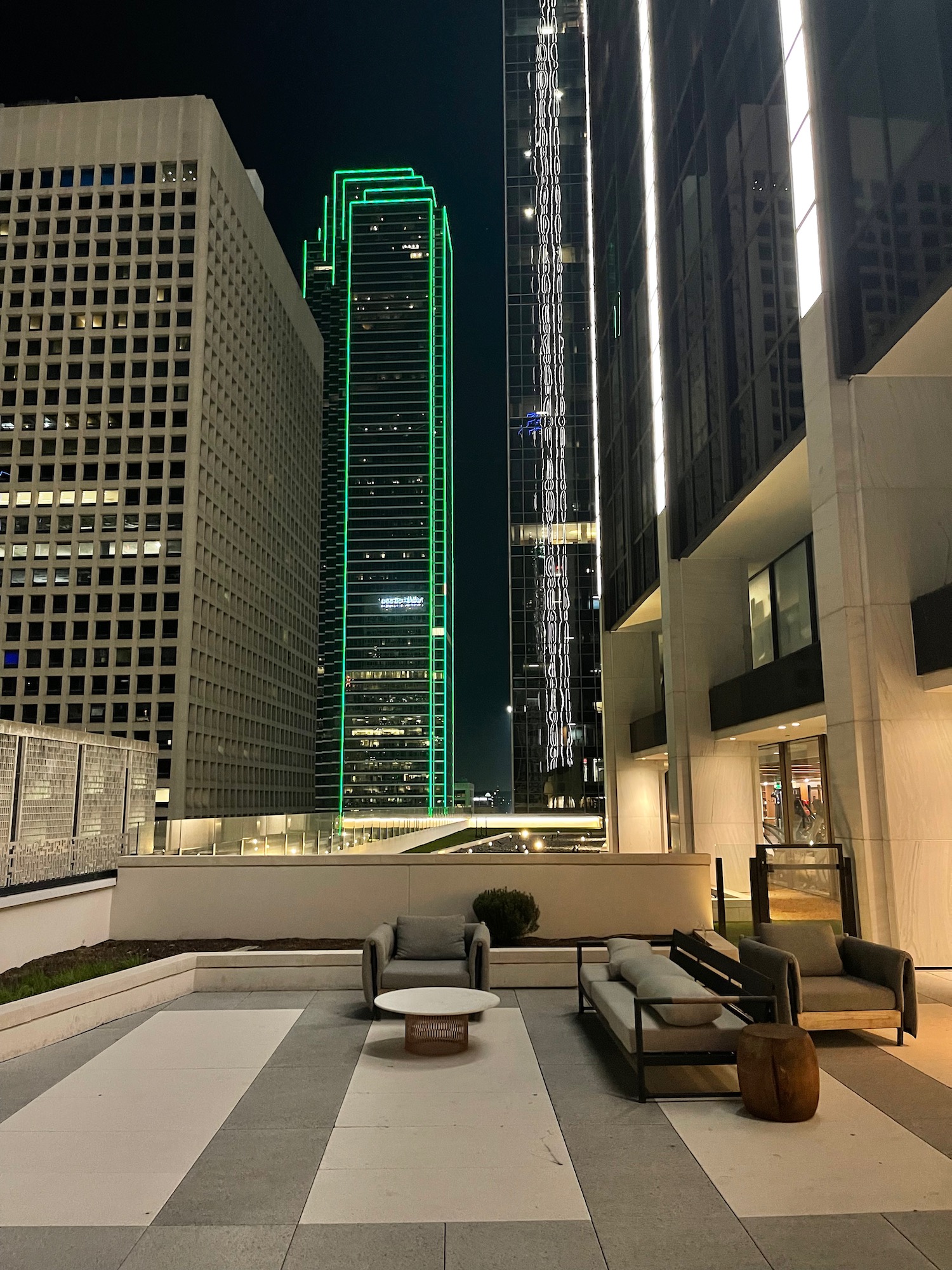 a rooftop patio with a green lit up building in the background