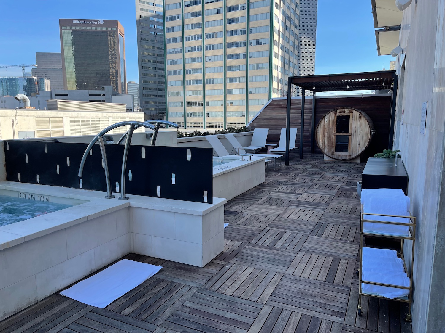 a rooftop pool with a hot tub and a large building in the background