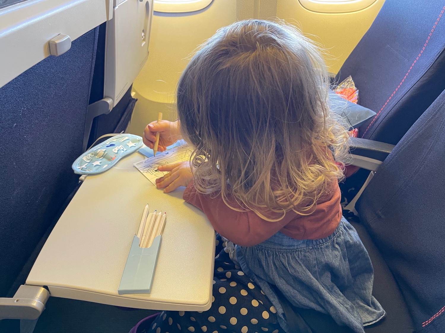 a child sitting at a table with pencils and a piece of paper