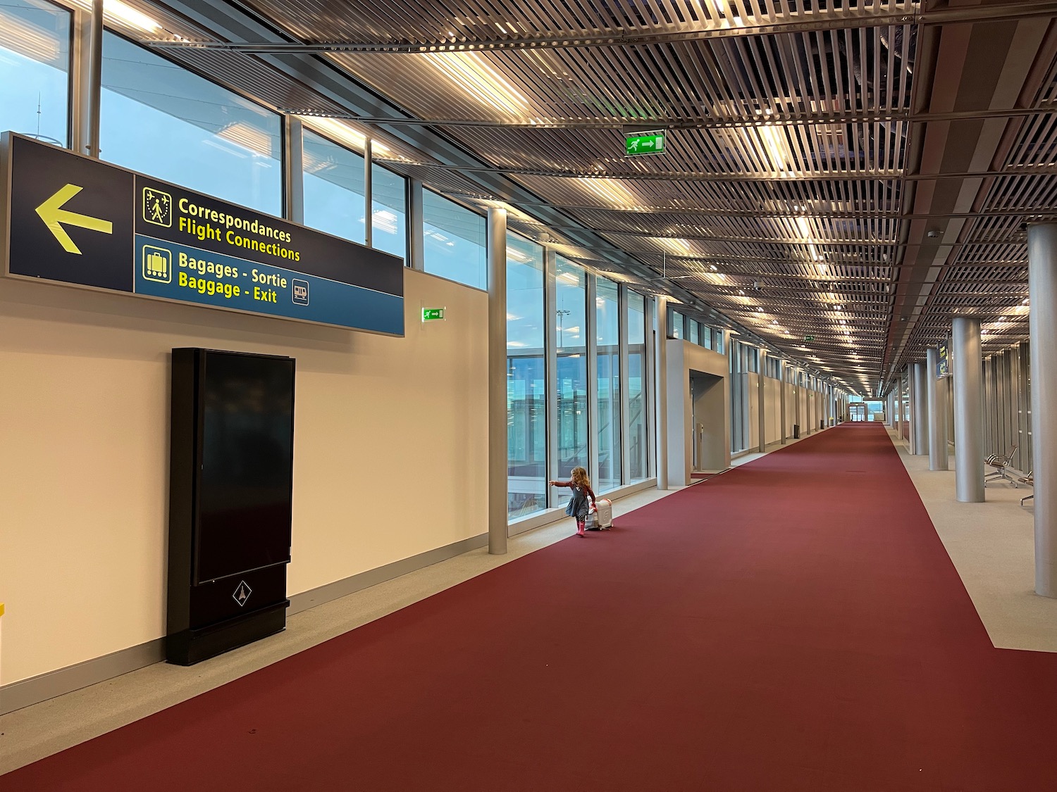 a red carpeted hallway with a sign and a child sitting on it