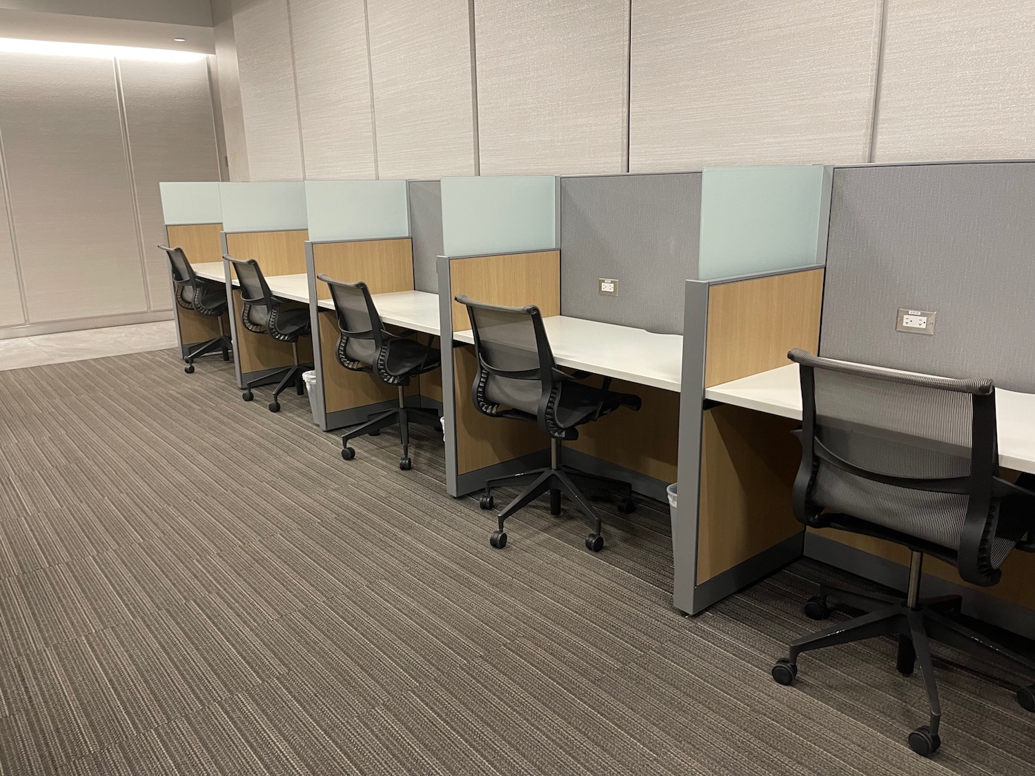 a row of cubicles with chairs and desks