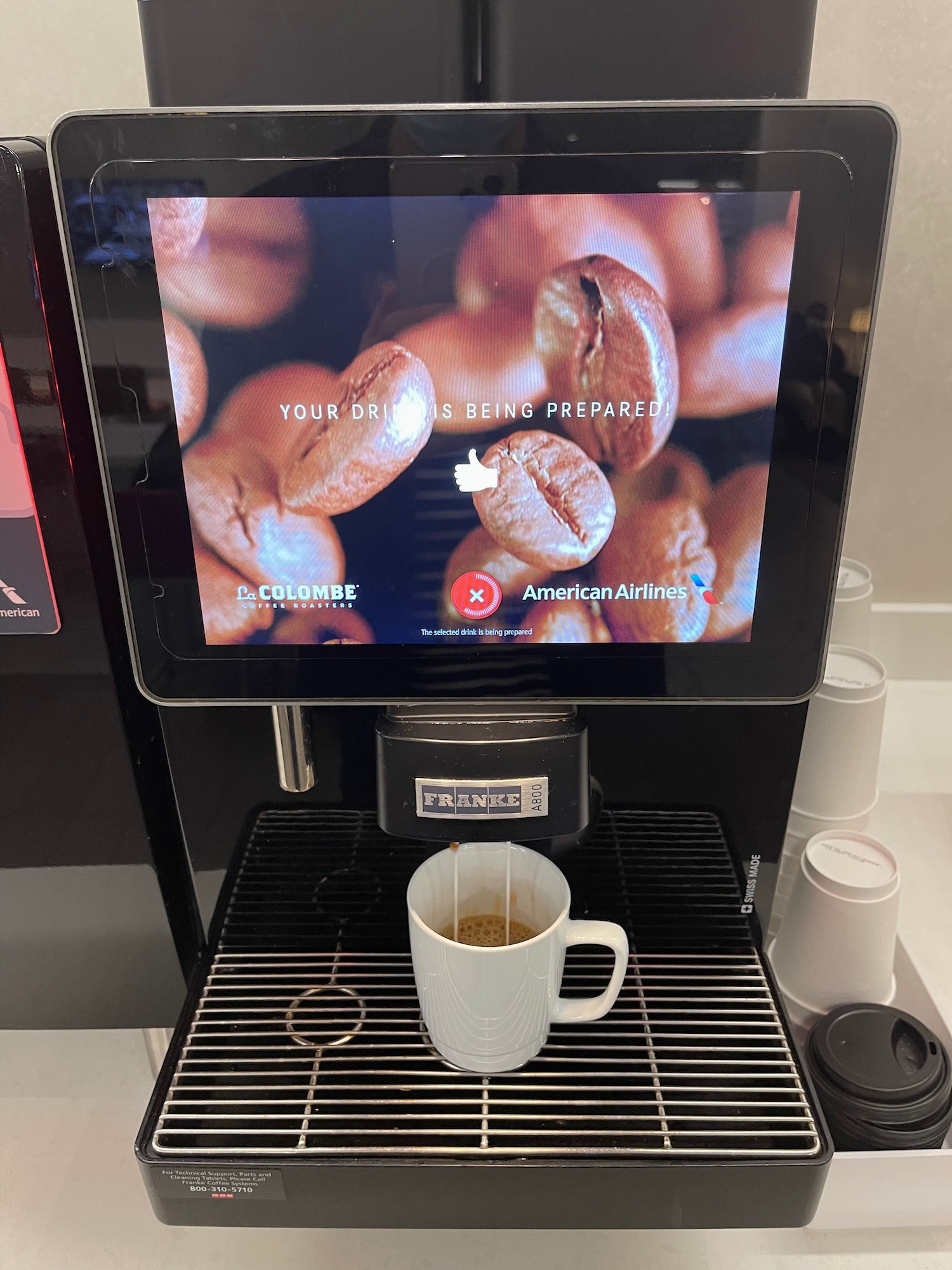 a coffee machine with a screen and a cup of coffee