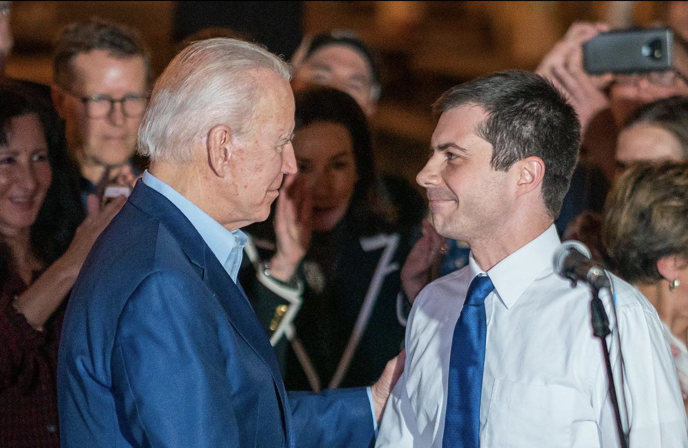 a man in a suit and tie shaking hands with another man in a crowd