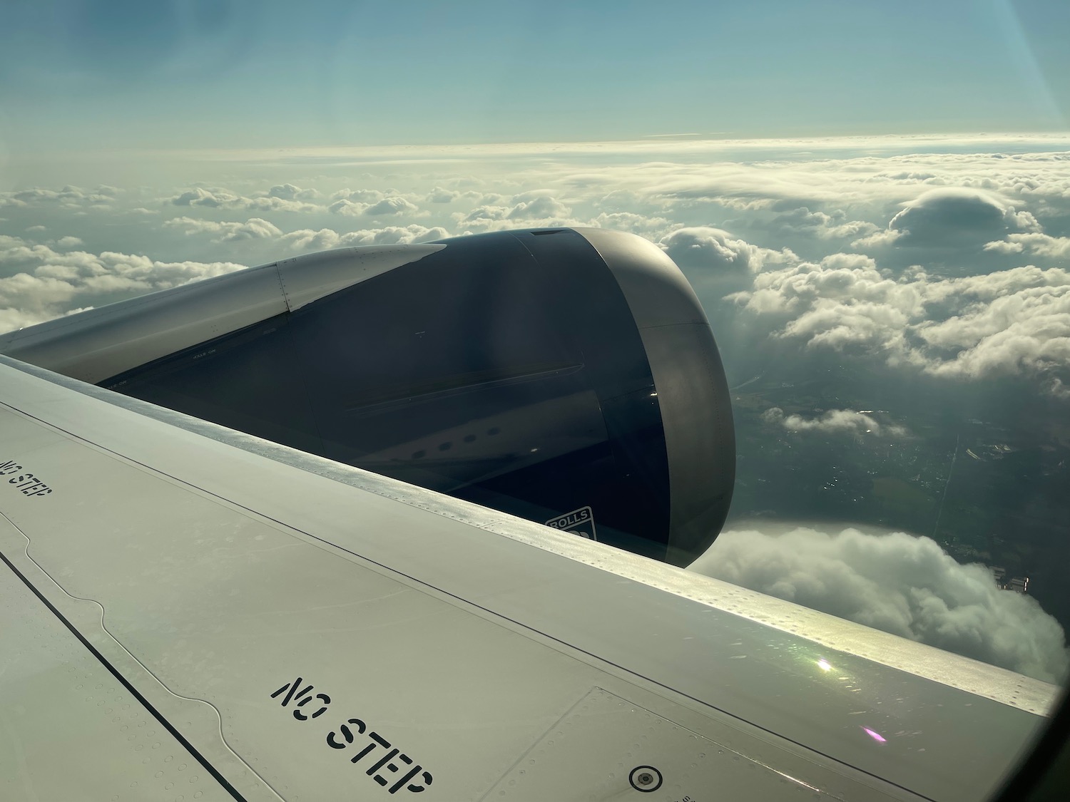 an airplane wing with a jet engine and clouds