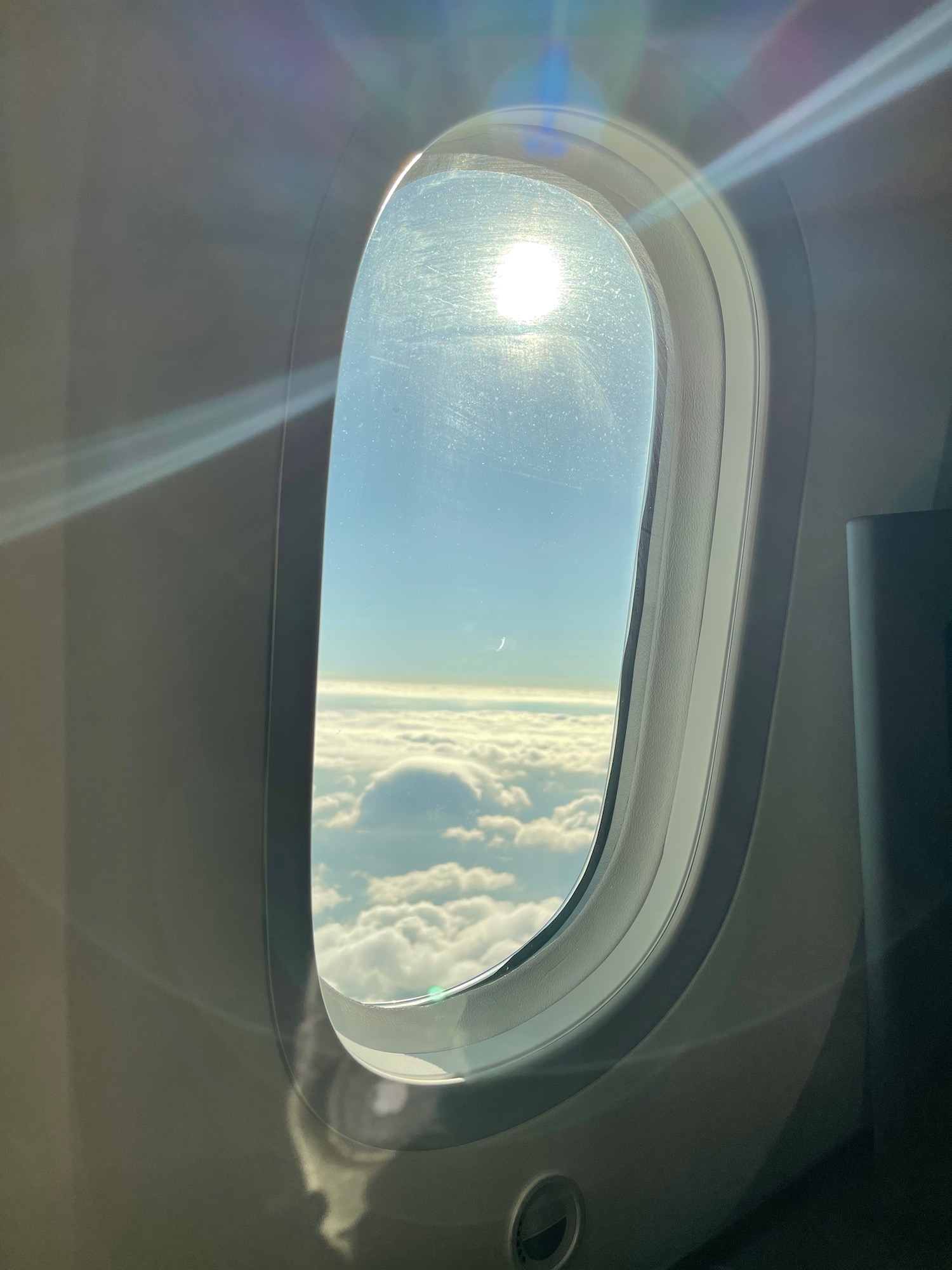 a window with clouds and the sun shining through it