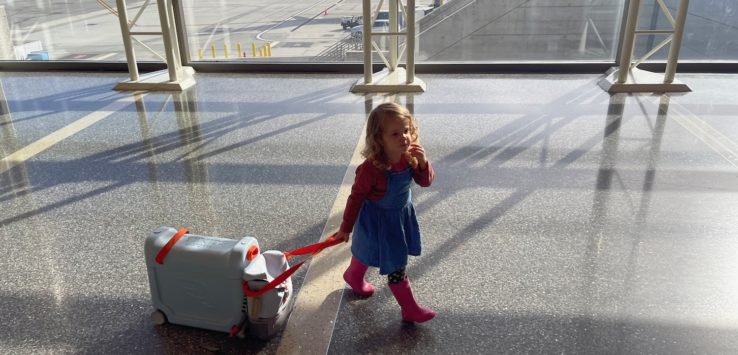 a girl walking with a suitcase in an airport