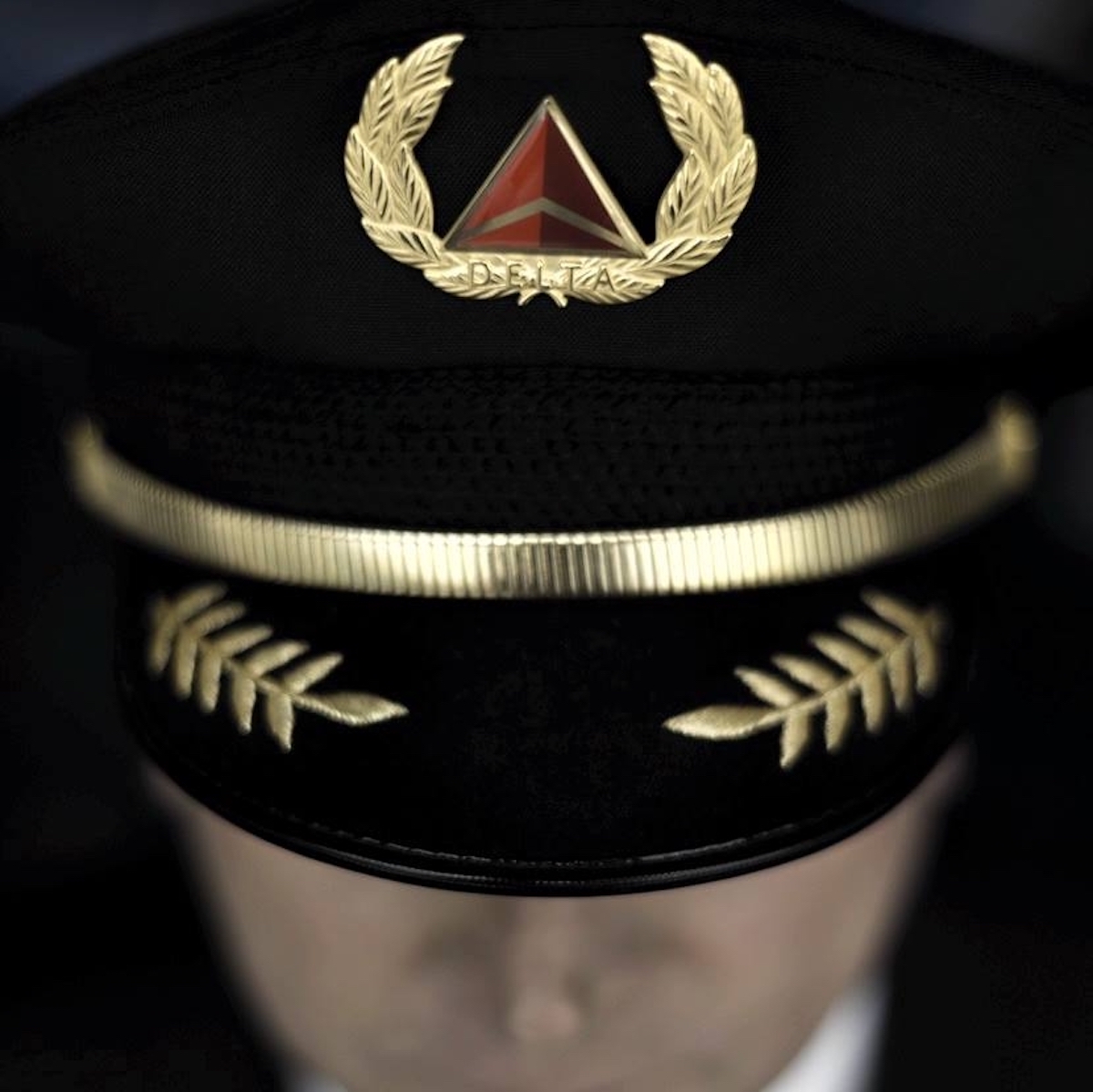 a person wearing a black hat with gold leaves and a red triangle on it
