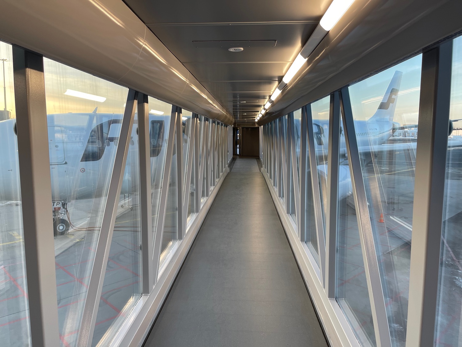 a long walkway with windows and a plane in the background