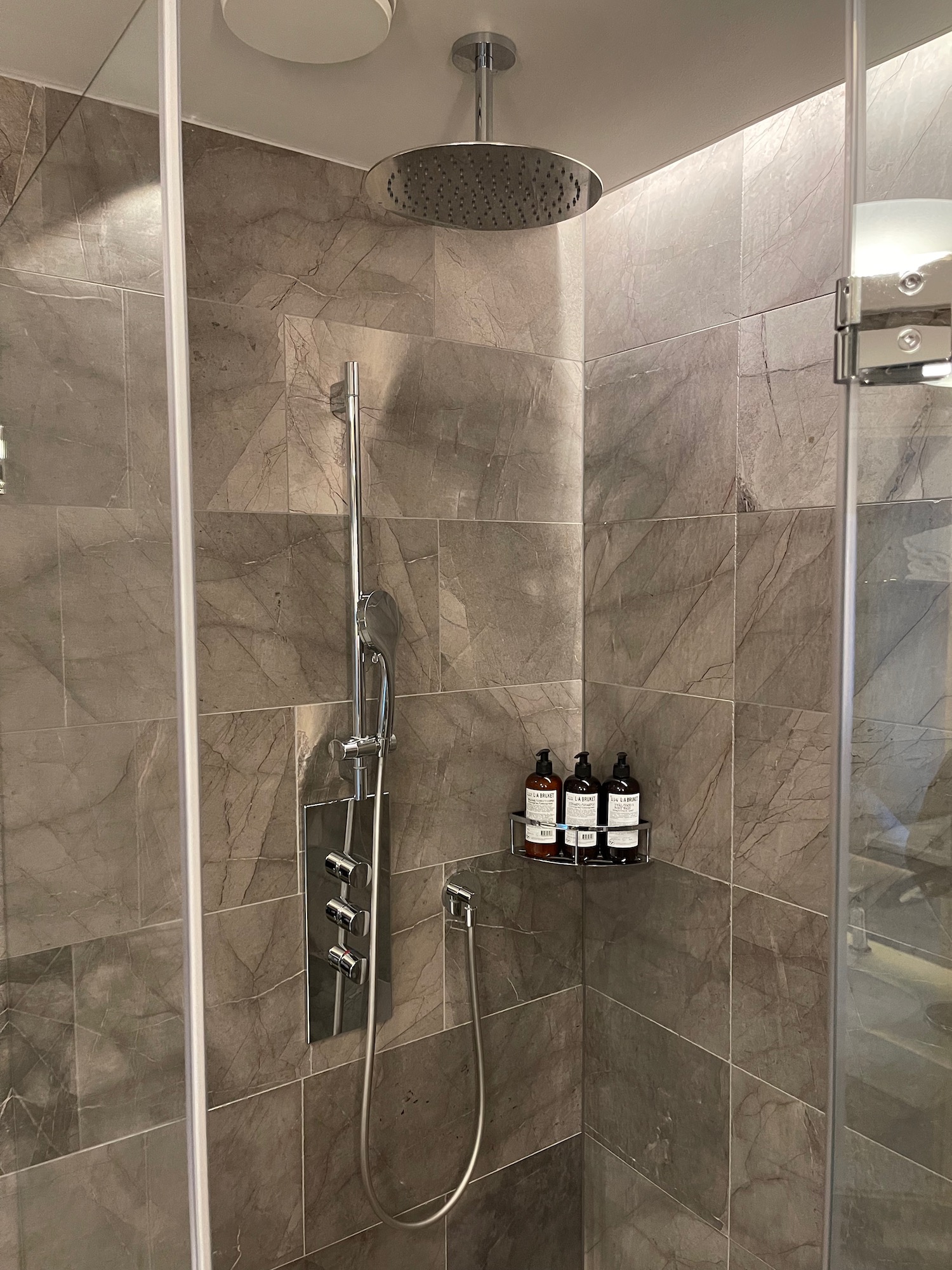 a shower with a shower head and bottles of essential oils