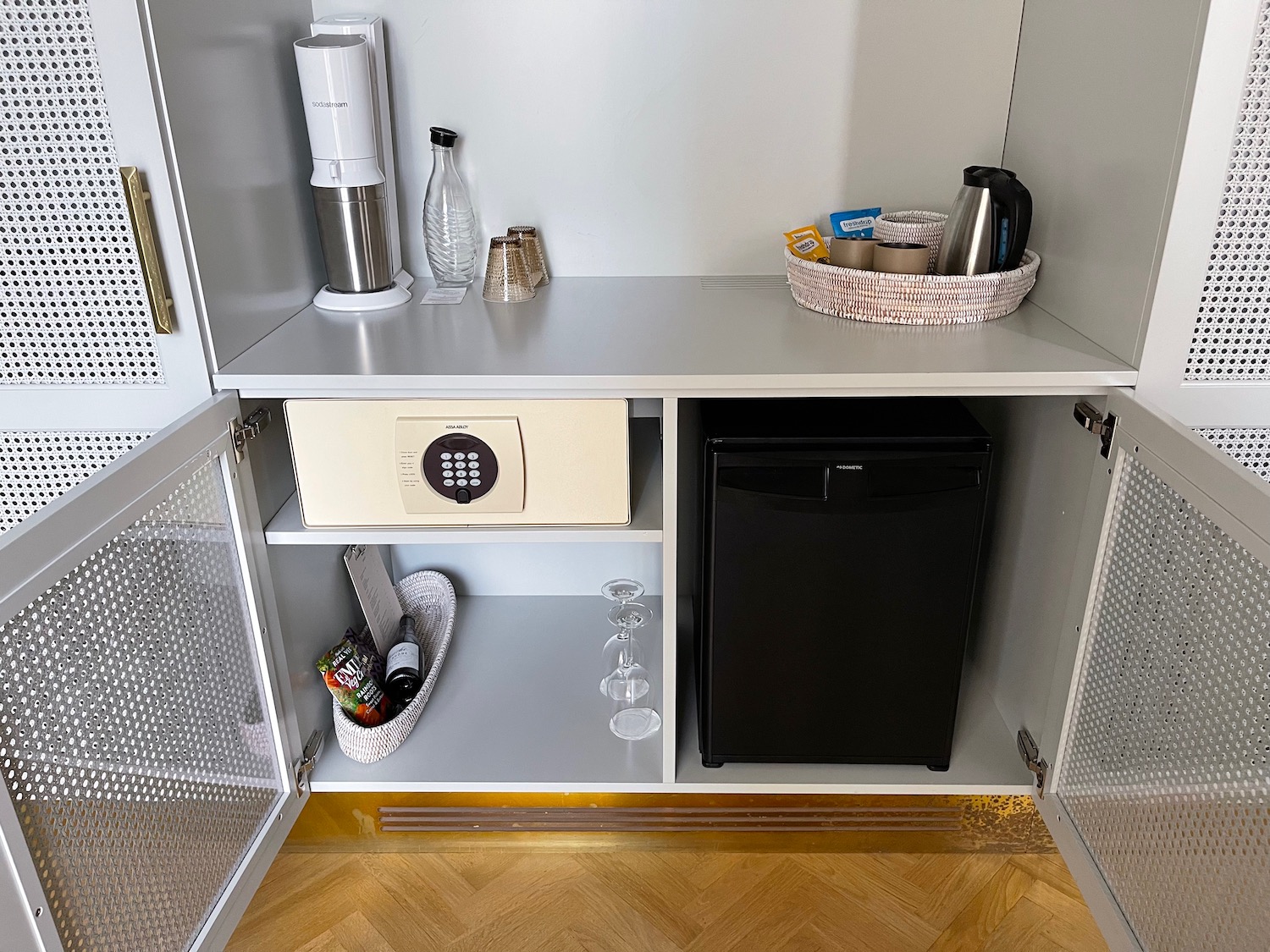 a small white cabinet with a small black refrigerator and a black refrigerator