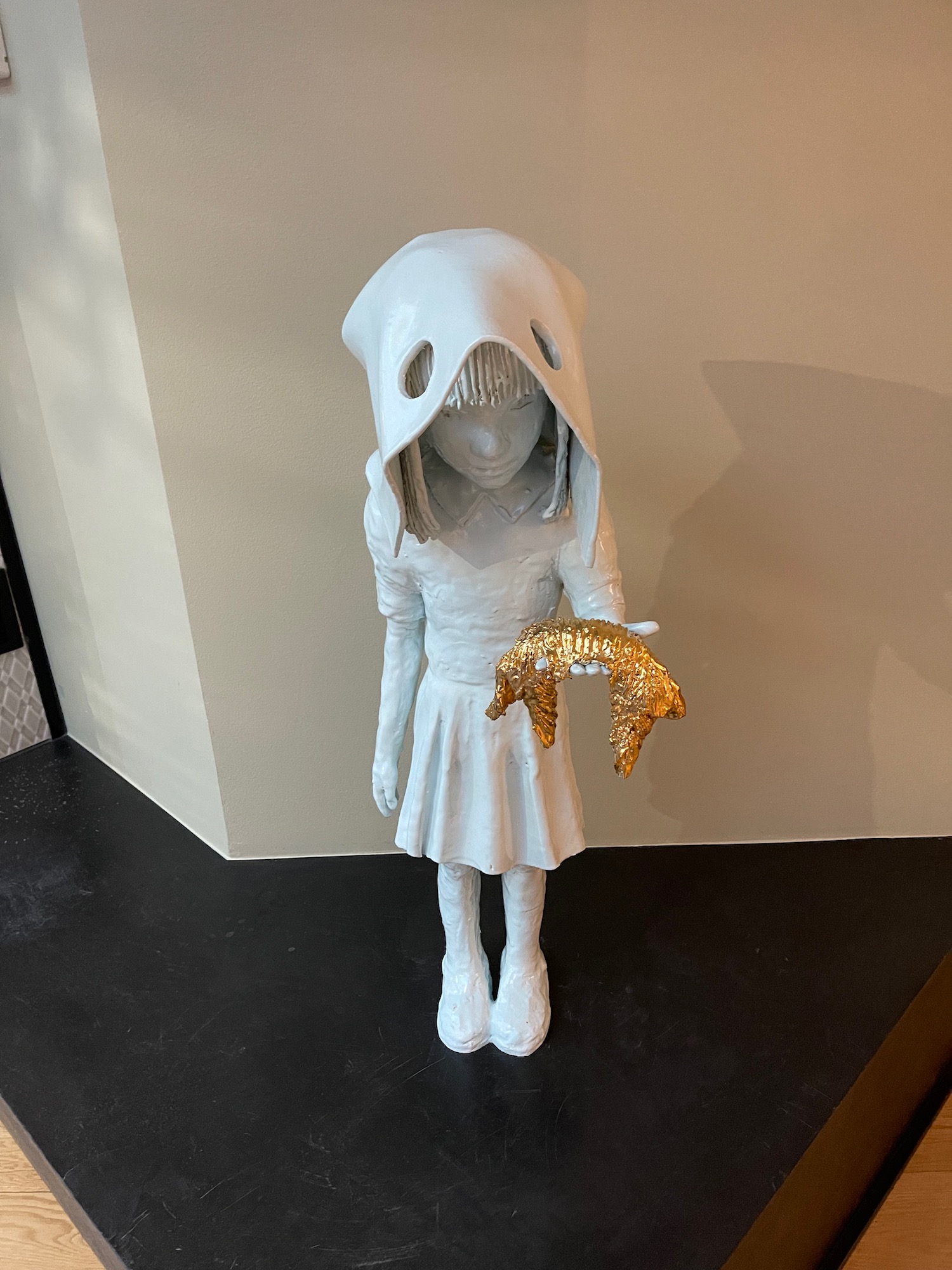 a statue of a girl wearing a hood and holding a gold star