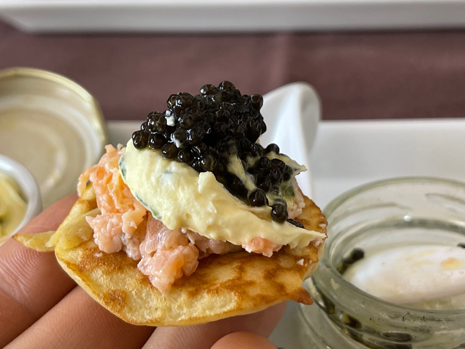 a person holding a small cracker with black caviar