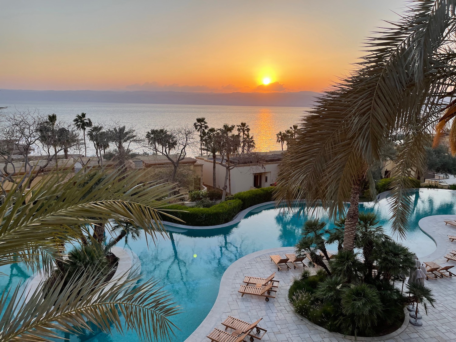 a pool with palm trees and a sunset