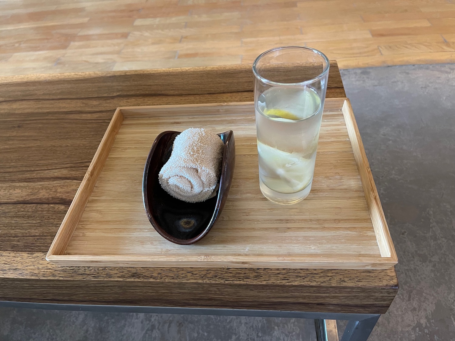 a glass of water and a plate of food on a wooden tray