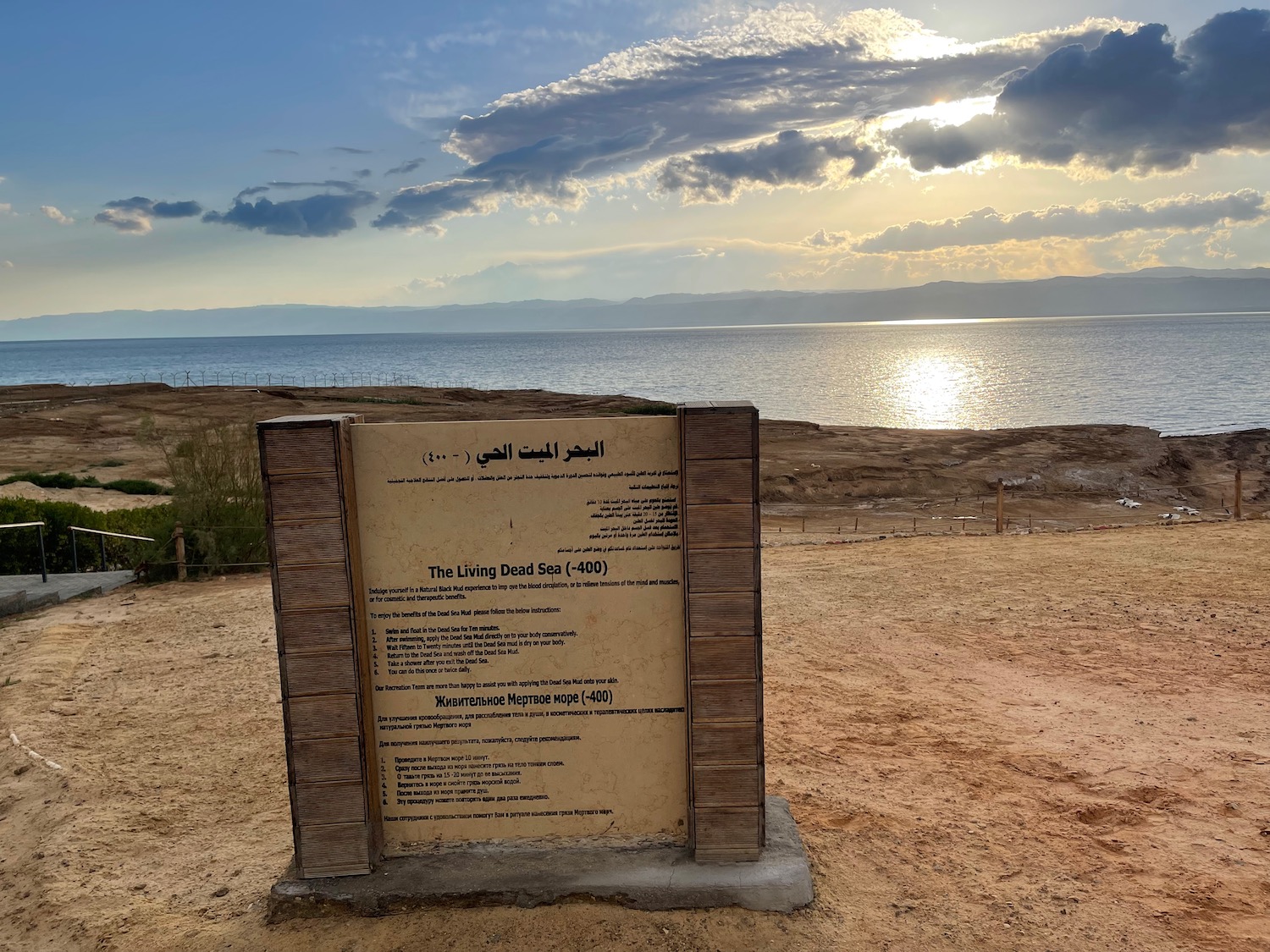 a sign on a sandy area with water in the background