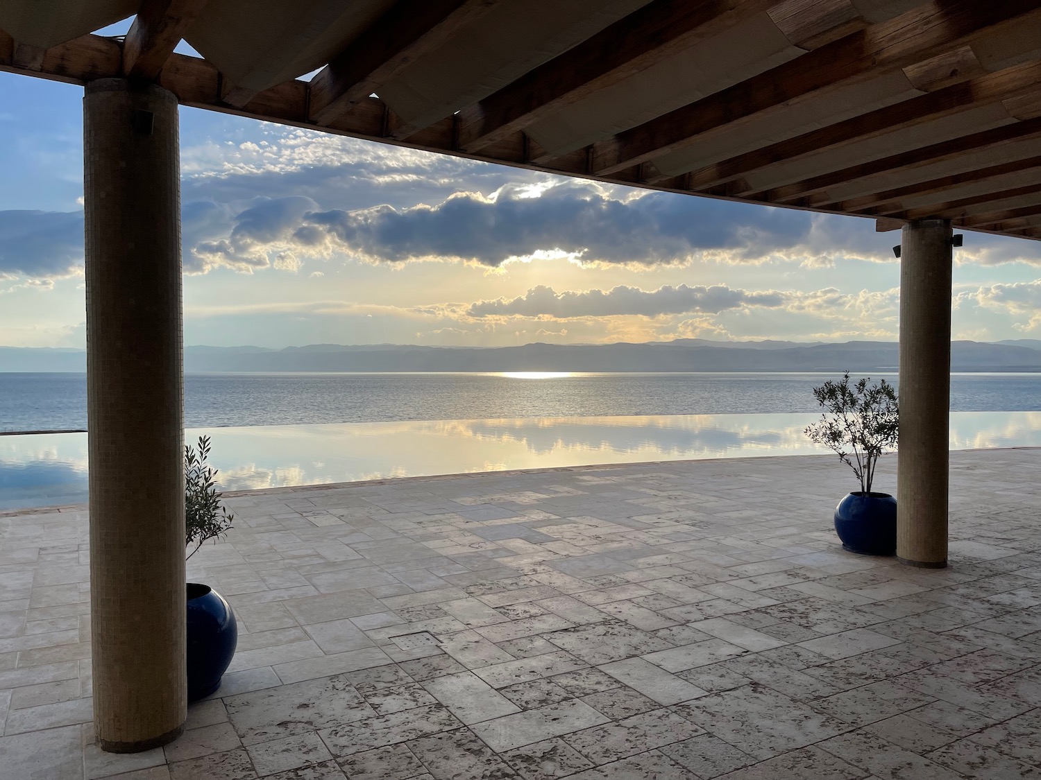 a covered patio with a view of the ocean and mountains in the distance