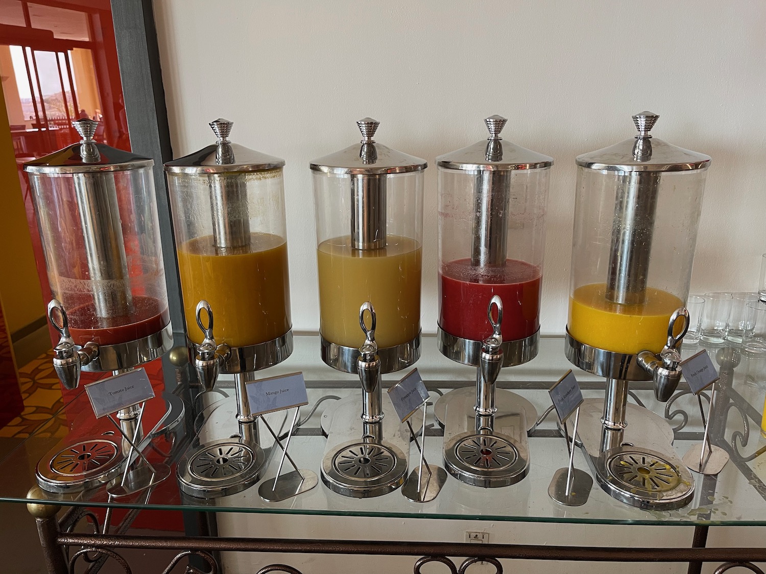 a group of juice dispensers on a glass table