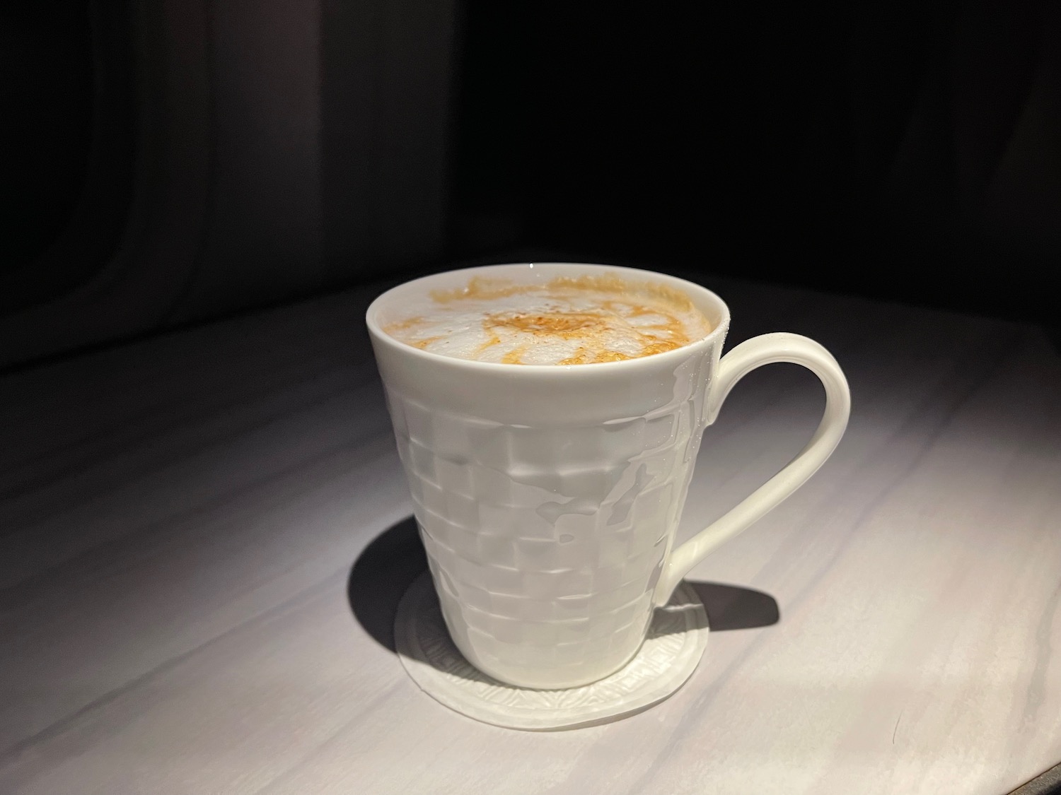 a white cup with a brown foamy liquid in it