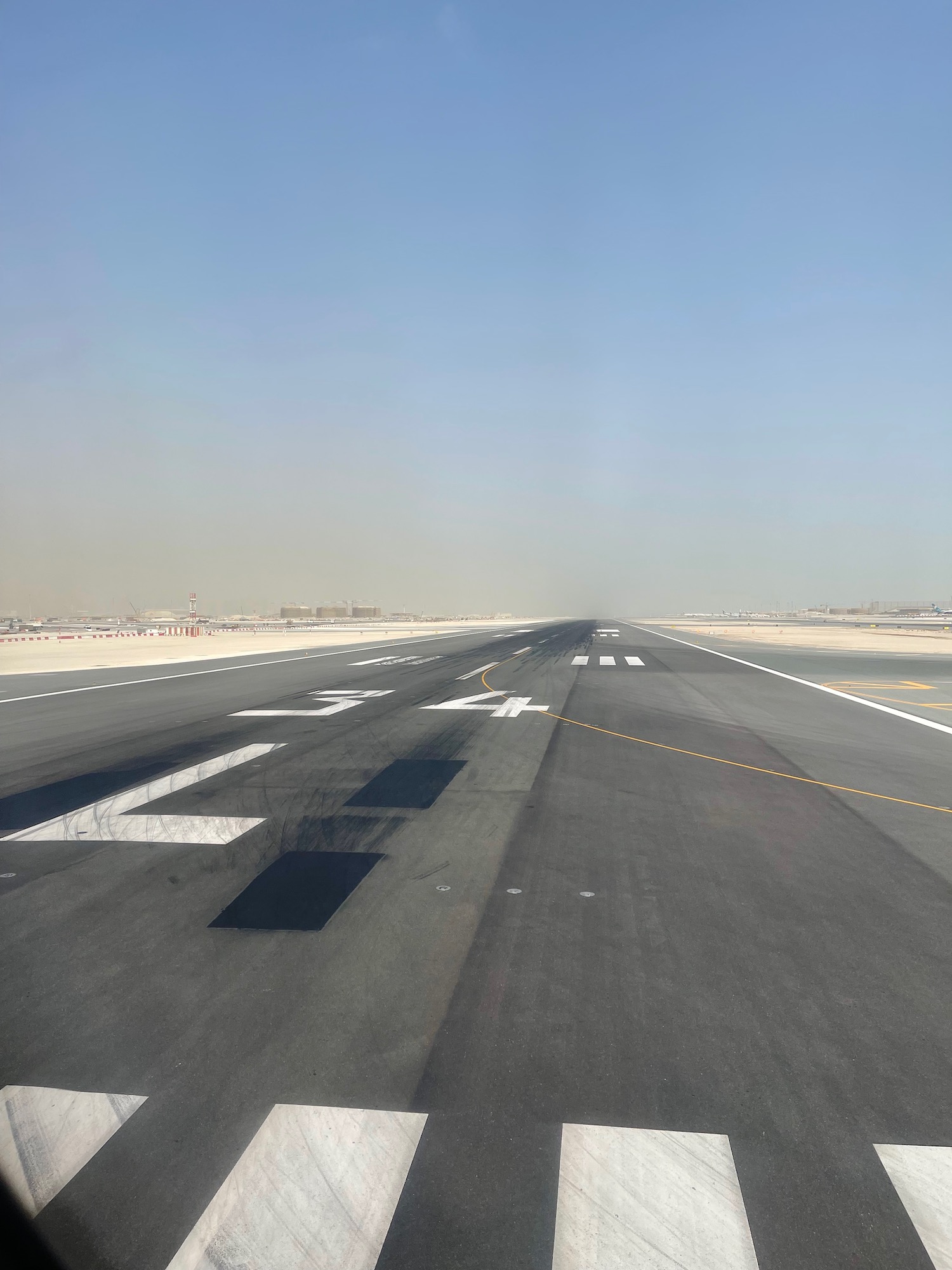 a runway with white markings and a blue sky