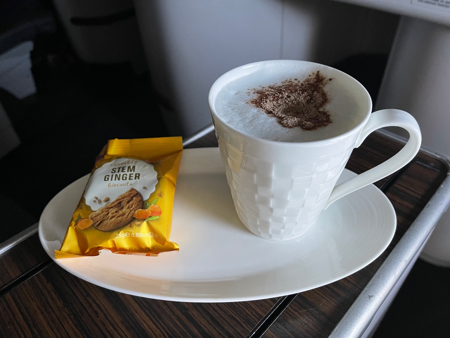 a white cup with foam and a bag of gingerbread