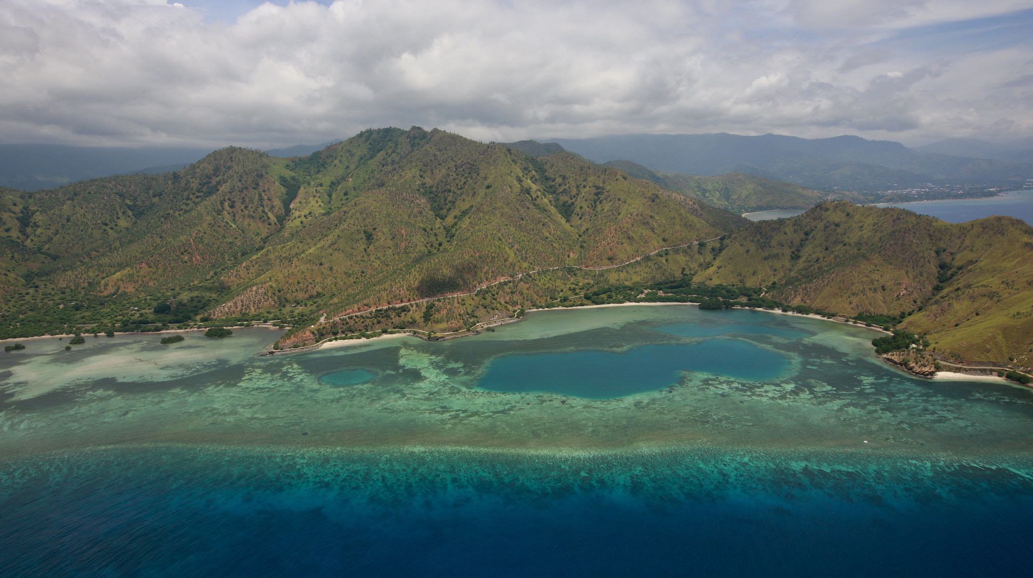 a blue water and green hills