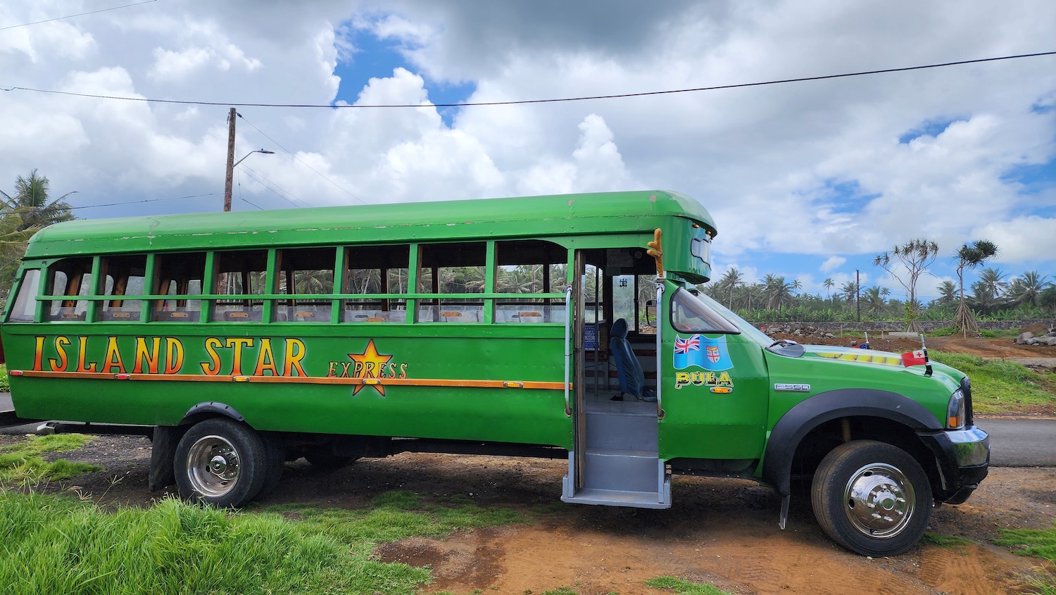 a green bus parked on a dirt road