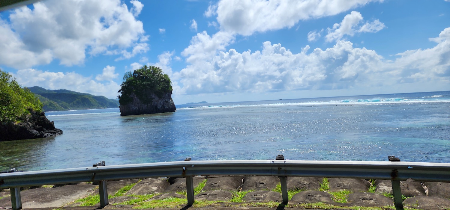 a road with a rock in the water