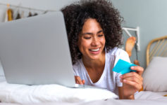 a woman lying on a bed looking at a laptop