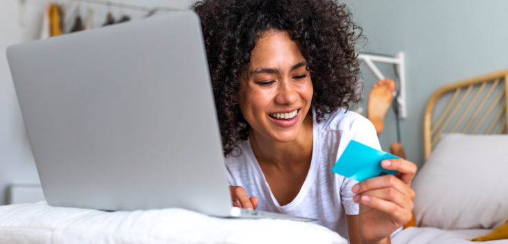 a woman lying on a bed looking at a laptop