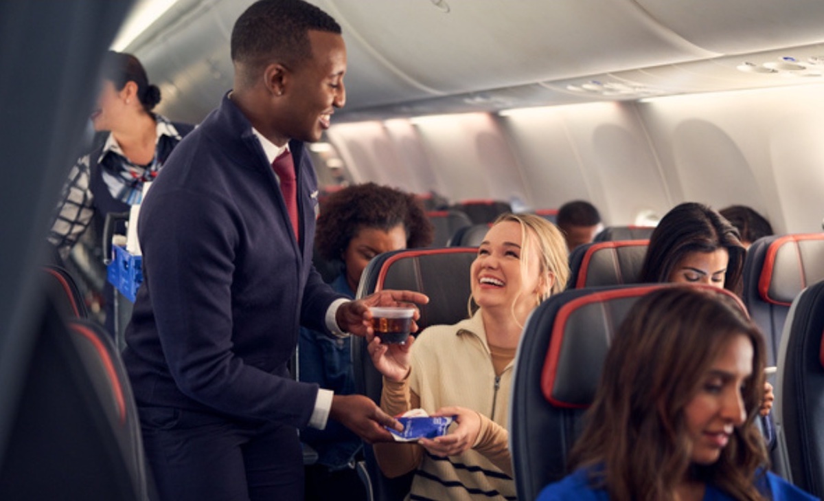 a man giving a drink to a woman on an airplane