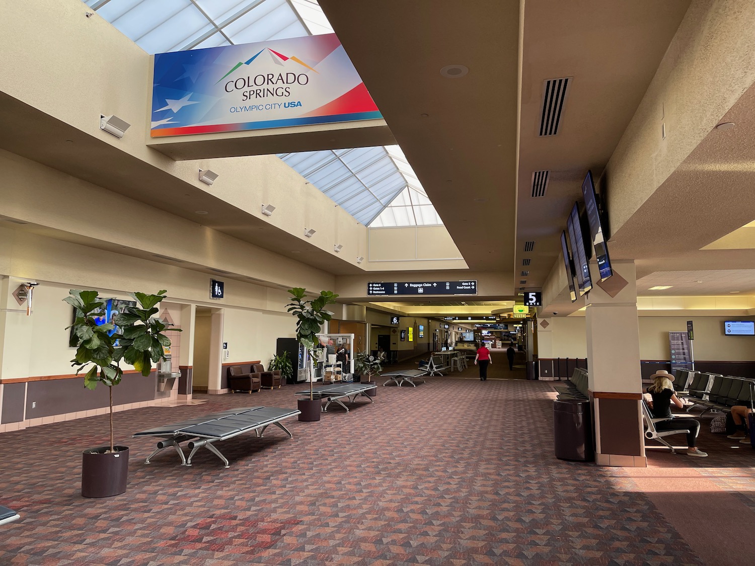 a large airport terminal with a sign and chairs