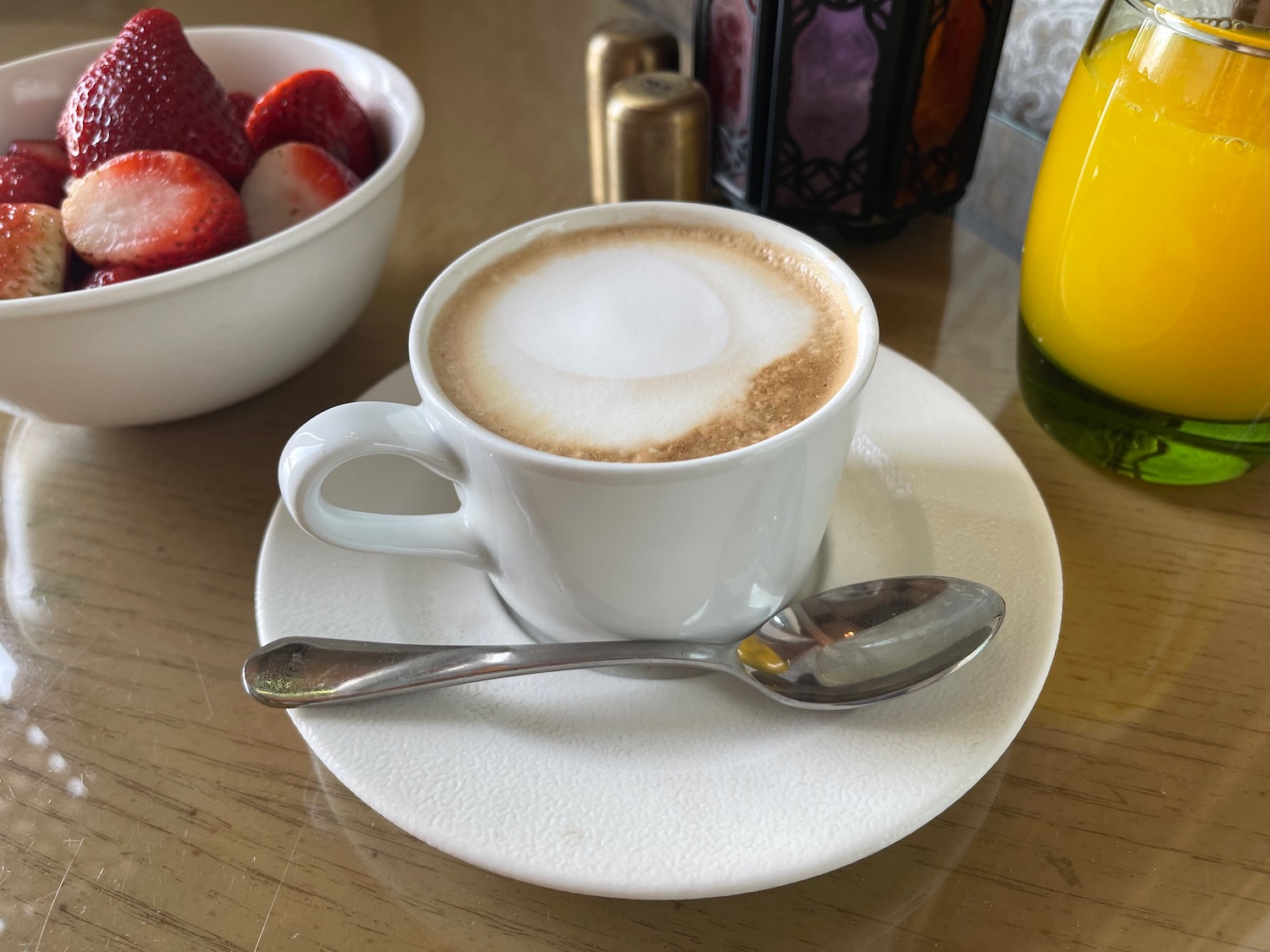 a cup of coffee with a spoon and a bowl of strawberries