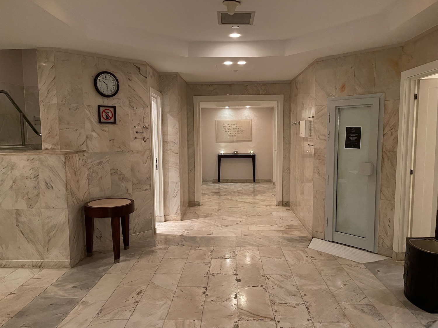 a marble hallway with a table and a clock