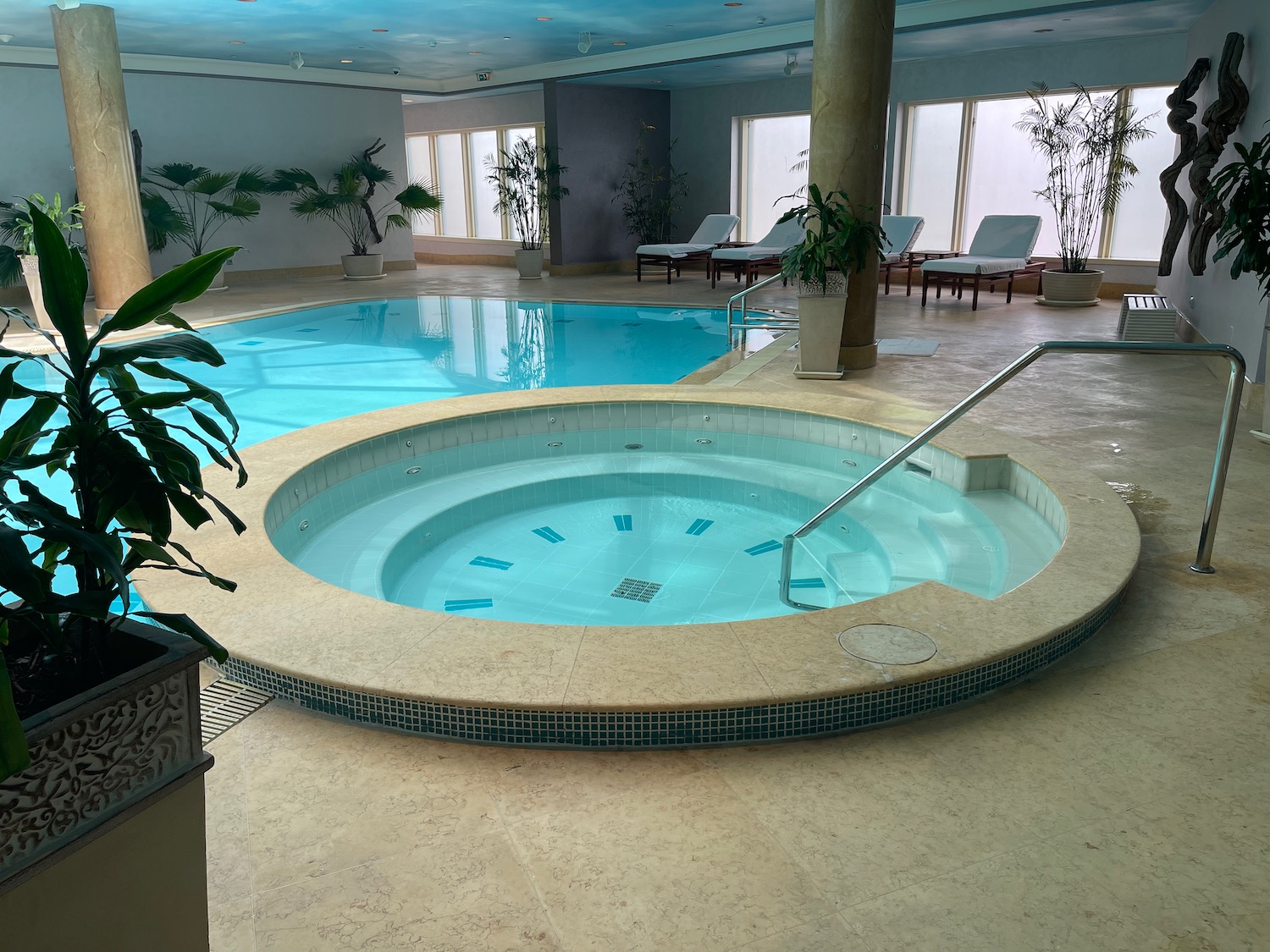 a pool with a hot tub and lounge chairs