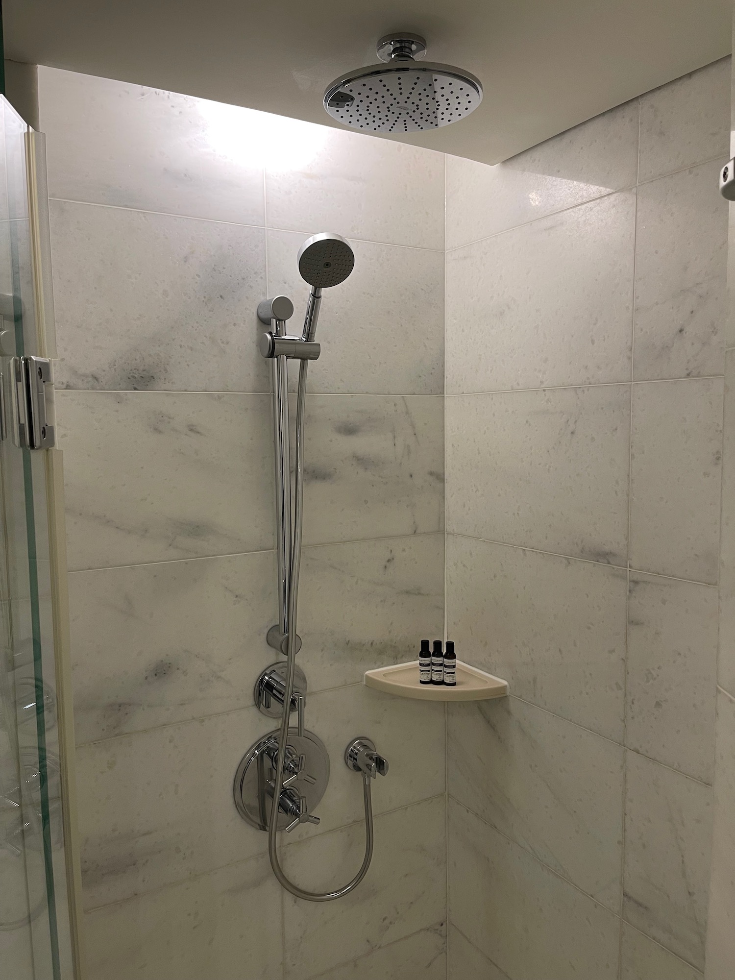a shower with a shower head and a small shelf