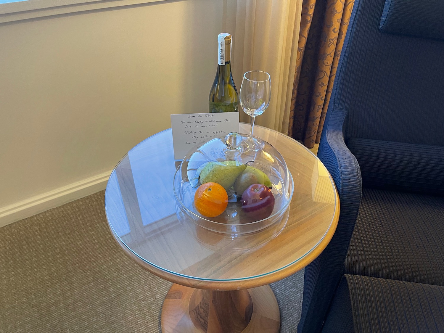 a glass bowl of fruit and a bottle of wine on a table