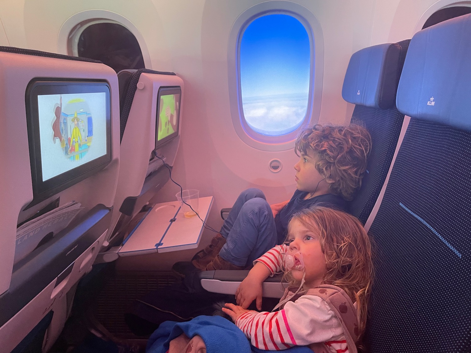 children sitting in an airplane with a screen on the side