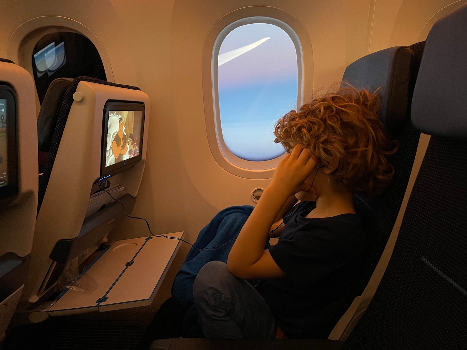 a boy sitting in an airplane with a screen on