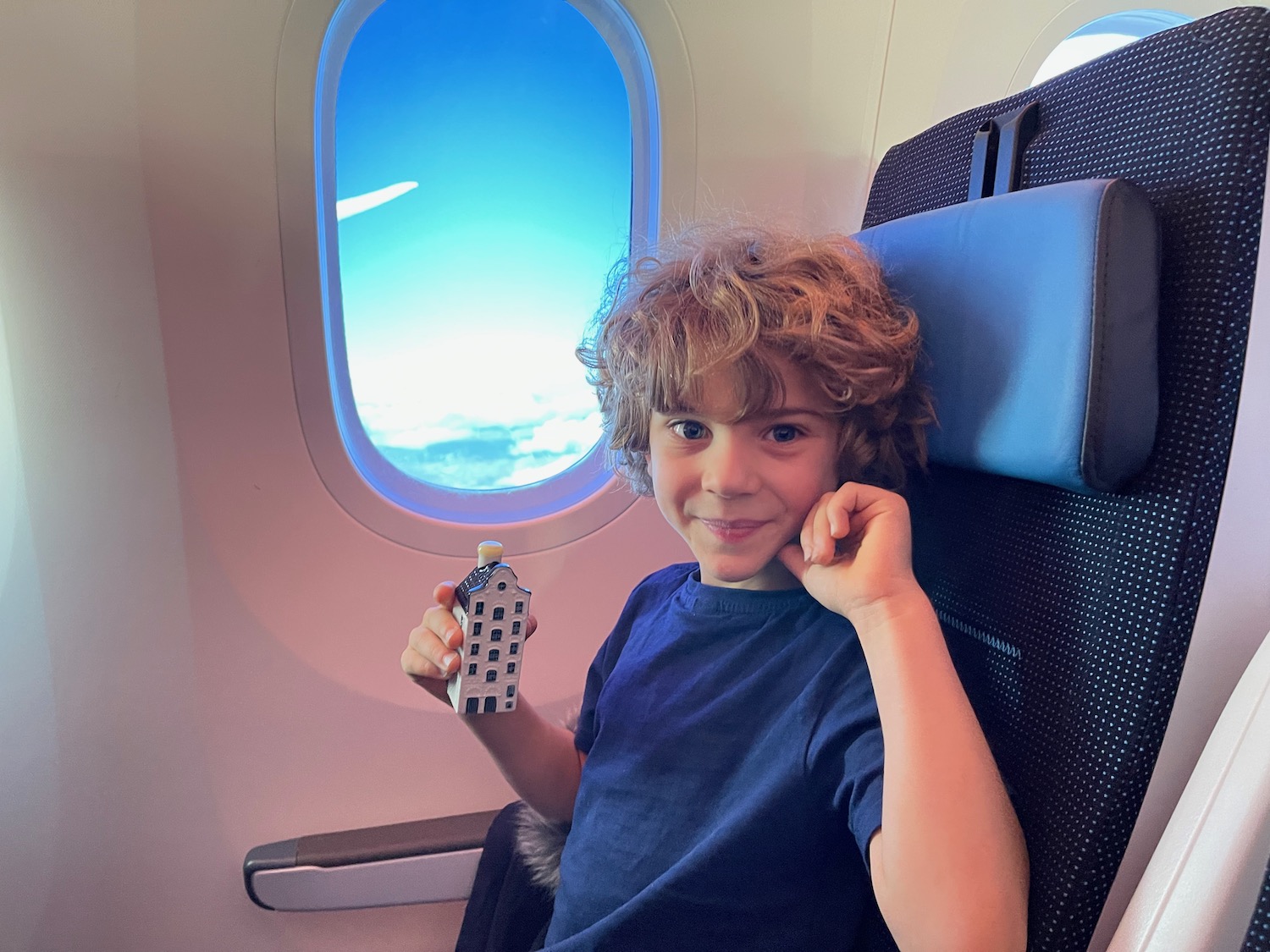 a boy sitting in an airplane holding a model house