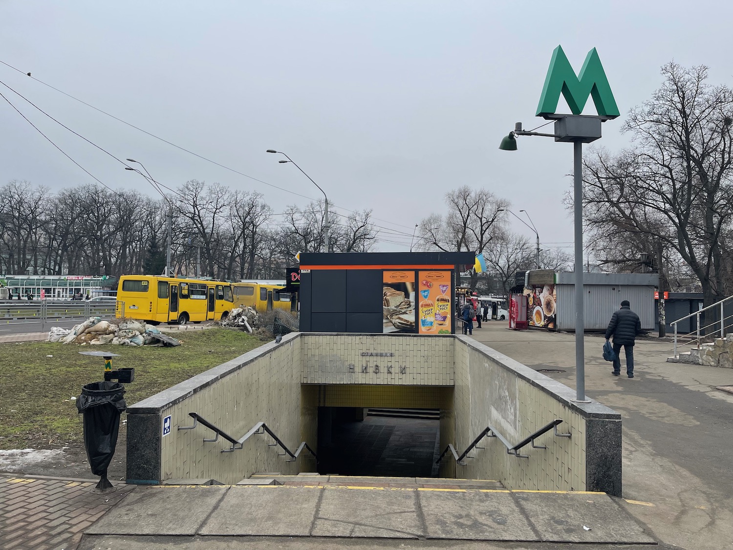 a subway entrance with a sign and a bus stop