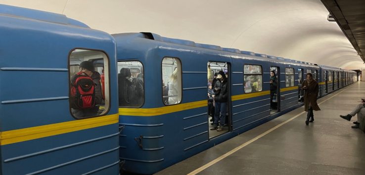 a blue train with people standing in front of it