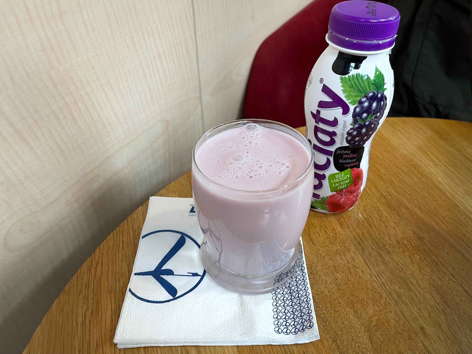 a glass of pink liquid next to a bottle of yogurt